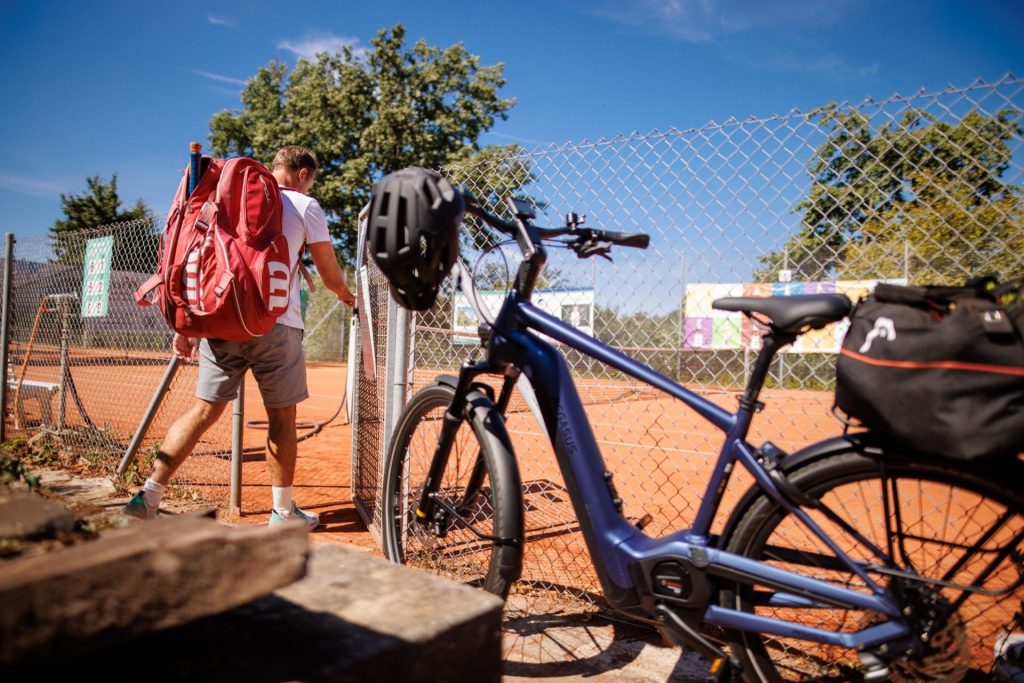 Ein Mann kam mit dem Fahrrad zum Tennistraining.